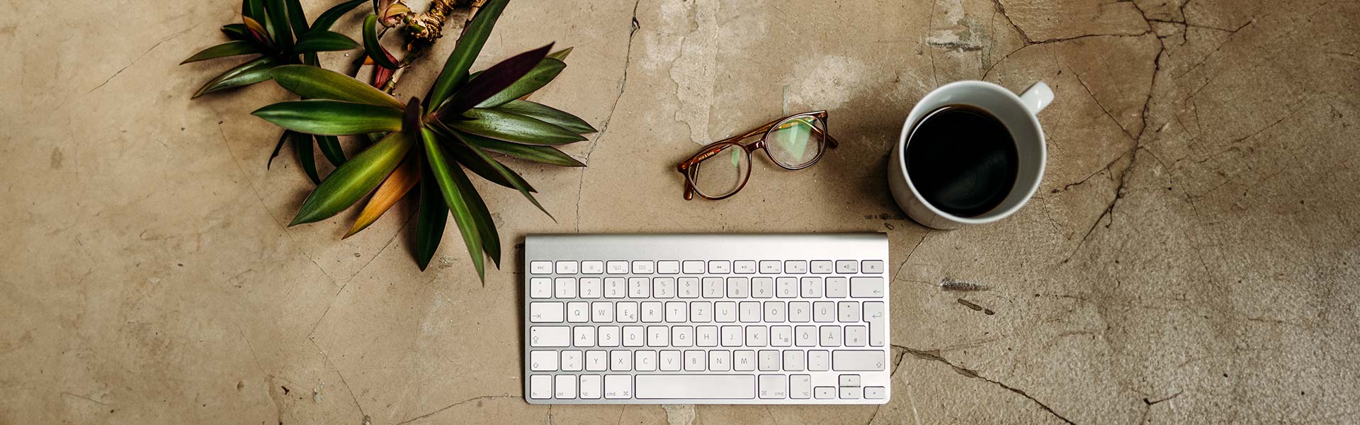 Schreibstisch mit Computer Tastatur, Brille und Kaffee